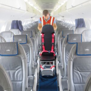 Starfsmaður flytur hjólastól um gang í flugvél